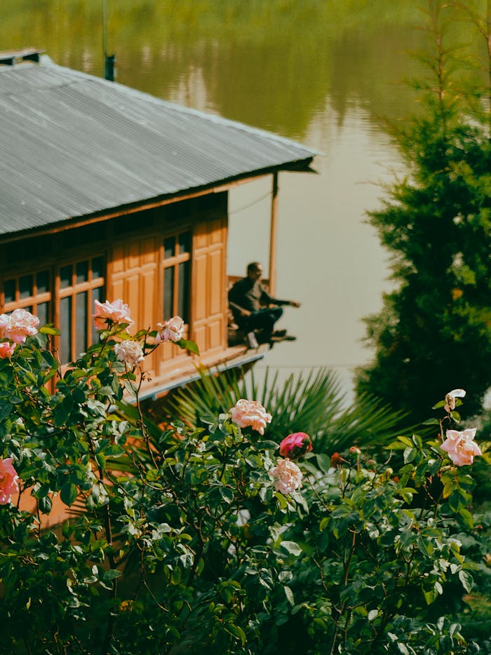 Crafting Captivating Headlines: Your awesome post title goes here A person enjoys a tranquil moment on a houseboat overlooking Dal Lake in Srinagar with blooming pink roses.